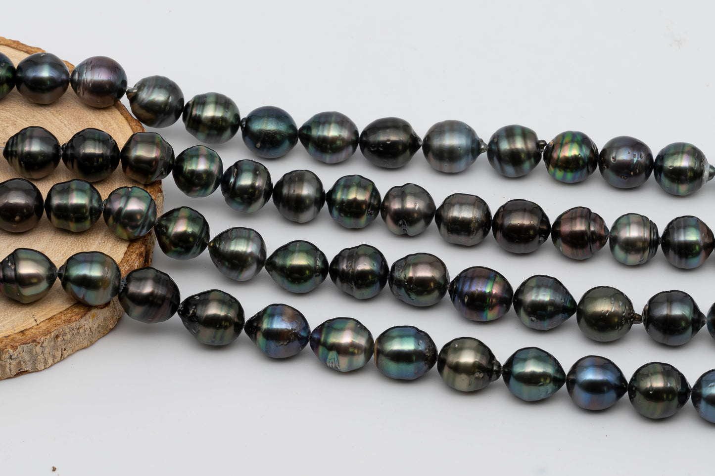 Tahitian Pearl drop shape full strand on top of a circle wood.