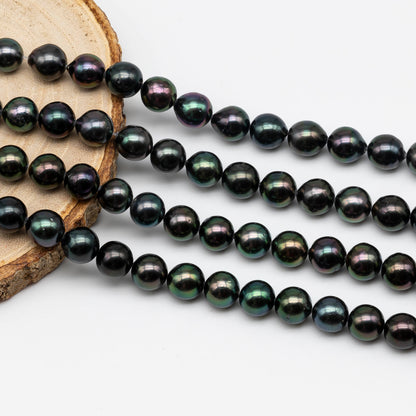 Beautiful near round peacock Tahitian Pearl in full strand display on top of a circle wood.