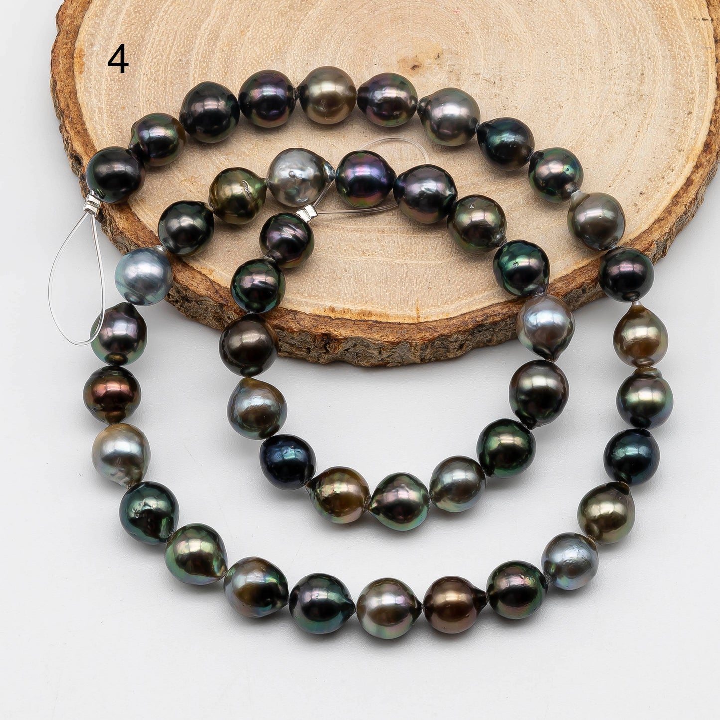 Tahitian Pearl drop in multi color full strand on top of a circle wood displaying item number 4.